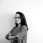 Portrait d'une collaboratrice souriante avec des lunettes, bras croisés
