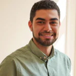 Portrait d'un jeune homme souriant, chemise verte, dans un contexte professionnel.