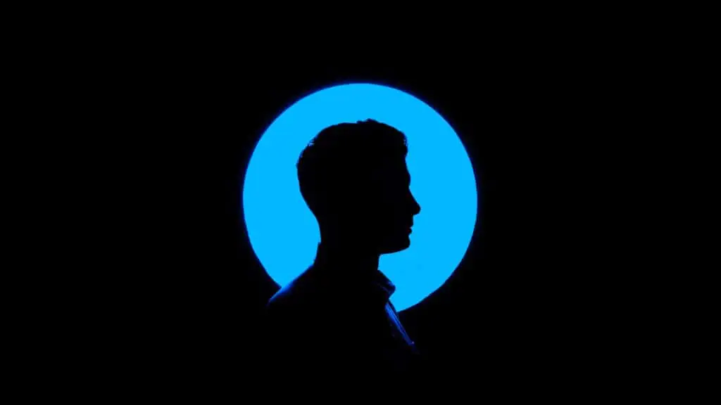 Silhouette de profil d'un homme se détachant sur un cercle de lumière bleue