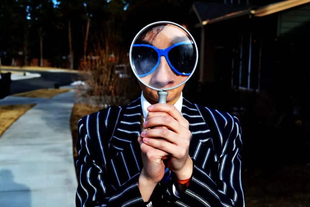 Collaborateur avec loupe, costume rayé. Recherche d'emploi.
