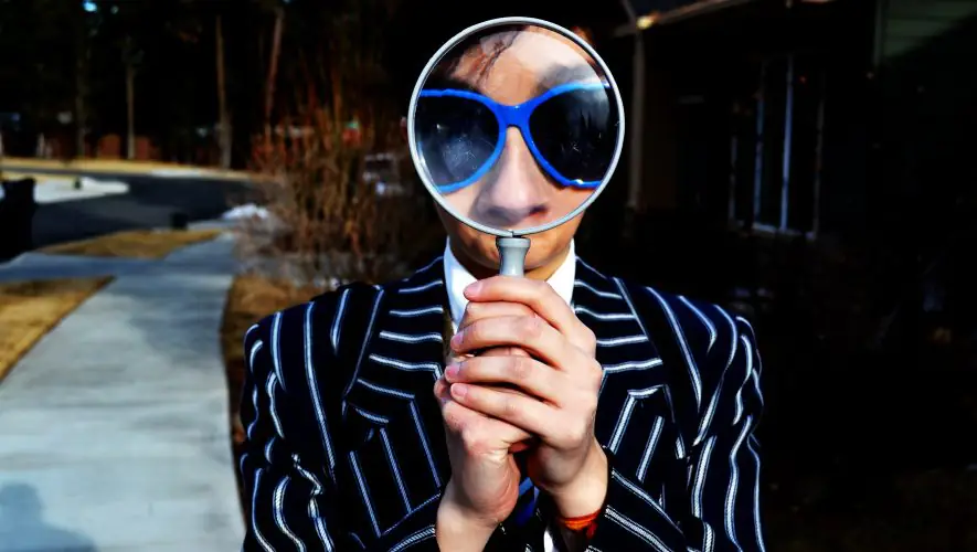 Collaborateur avec loupe, costume rayé. Recherche d'emploi.